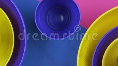 粉色蓝色黄色彩色塑料水碗未来色彩设计。 4k个镜头